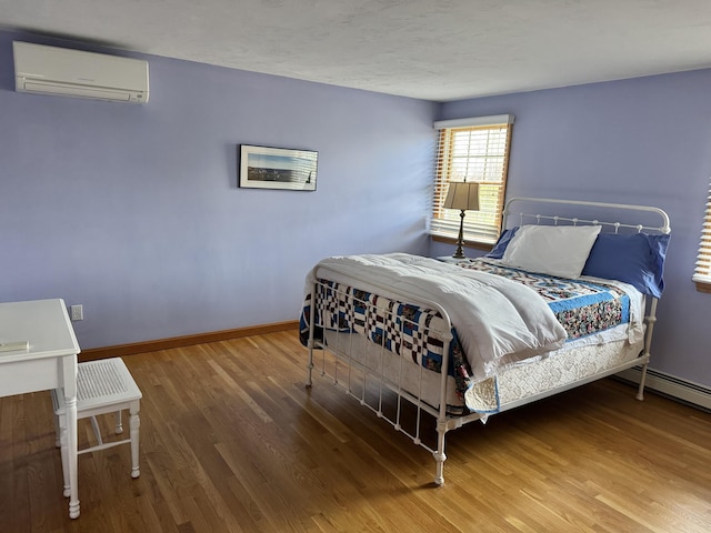 bedroom featuring baseboards, a wall mounted AC, and wood finished floors
