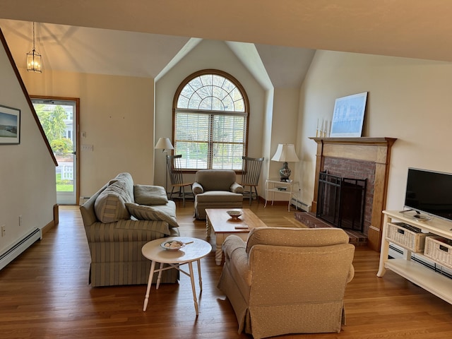 living room featuring a brick fireplace, vaulted ceiling, wood finished floors, and a baseboard radiator