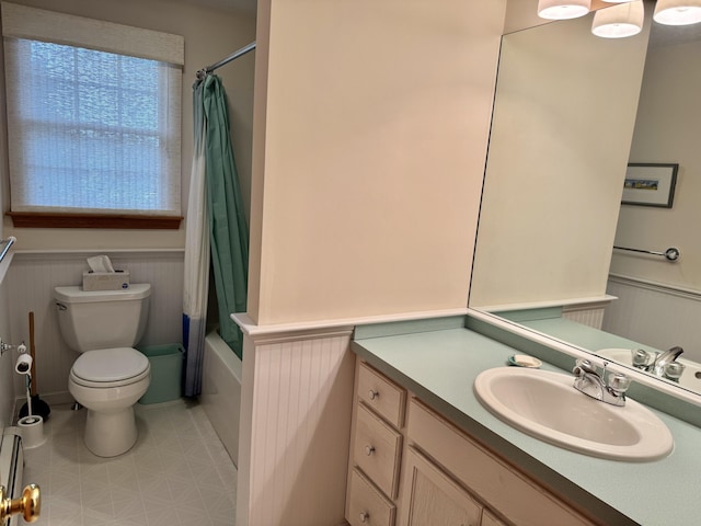 full bath with baseboard heating, vanity, toilet, a wainscoted wall, and shower / tub combo
