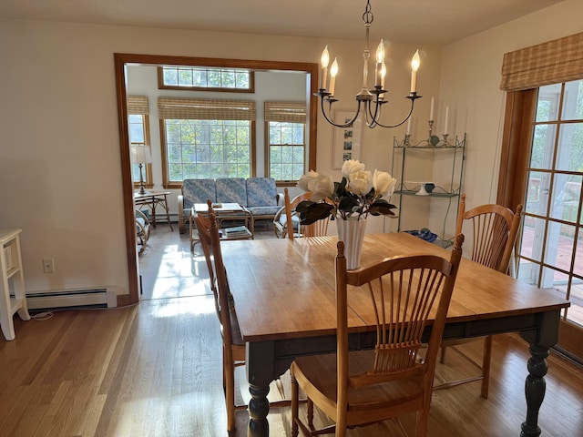 dining area with an inviting chandelier, wood finished floors, and baseboard heating