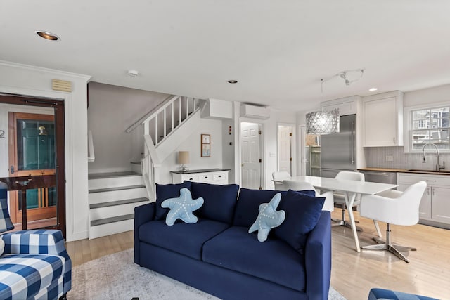 living area featuring stairs, recessed lighting, a wall unit AC, and light wood-style floors