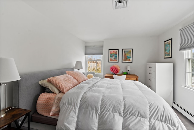 bedroom featuring a baseboard heating unit and visible vents