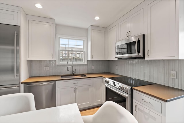 kitchen featuring recessed lighting, a sink, white cabinets, appliances with stainless steel finishes, and backsplash