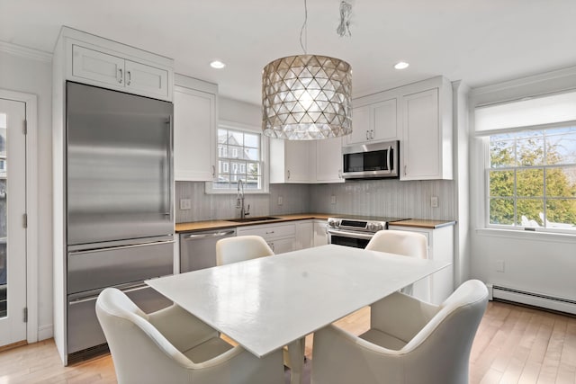 kitchen with appliances with stainless steel finishes, a sink, a wealth of natural light, and decorative backsplash