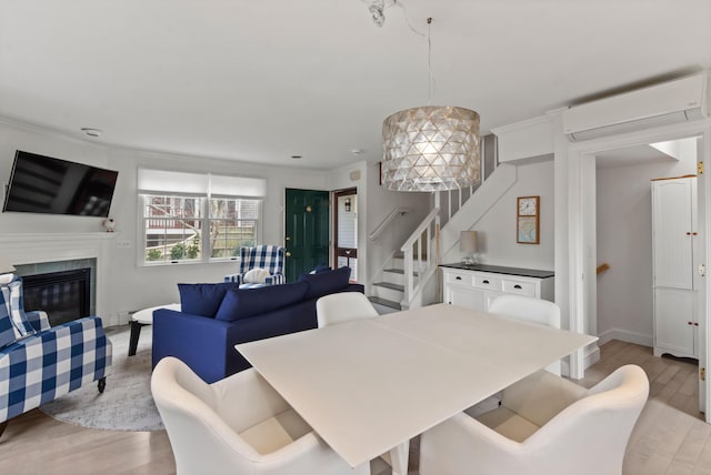 dining area featuring a high end fireplace, stairs, light wood-type flooring, a wall mounted air conditioner, and crown molding