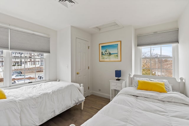 bedroom with dark wood-style floors, attic access, multiple windows, and visible vents