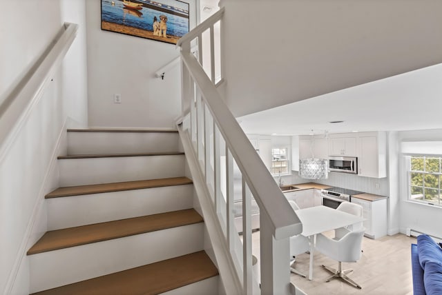 stairs featuring a baseboard radiator and wood finished floors