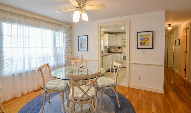 dining area with light wood-type flooring, ceiling fan, and baseboards