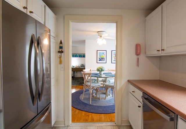 kitchen featuring a ceiling fan, white cabinetry, stainless steel appliances, and backsplash