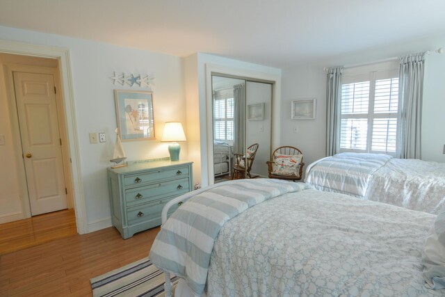 bedroom featuring light wood-style floors, baseboards, and a closet