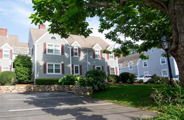 view of front facade with uncovered parking and a front lawn