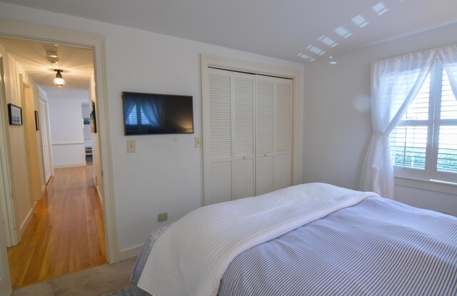 bedroom featuring a closet, light carpet, and baseboards