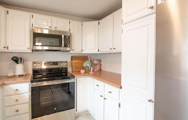 kitchen with stainless steel appliances, light countertops, backsplash, and white cabinetry