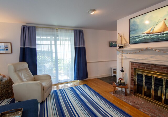 living room featuring a fireplace, baseboards, a wealth of natural light, and wood finished floors