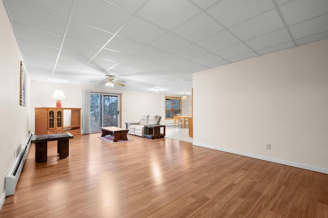 living room with wood-type flooring, a drop ceiling, and a baseboard radiator