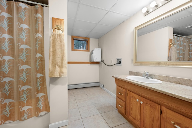 bathroom featuring tile patterned flooring, vanity, a drop ceiling, and baseboard heating