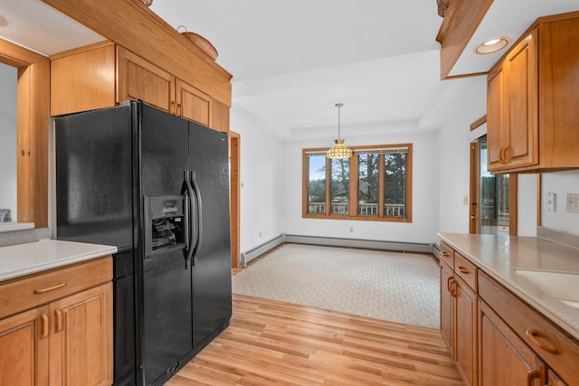 kitchen with decorative light fixtures, a baseboard radiator, a tray ceiling, light wood-type flooring, and black refrigerator with ice dispenser