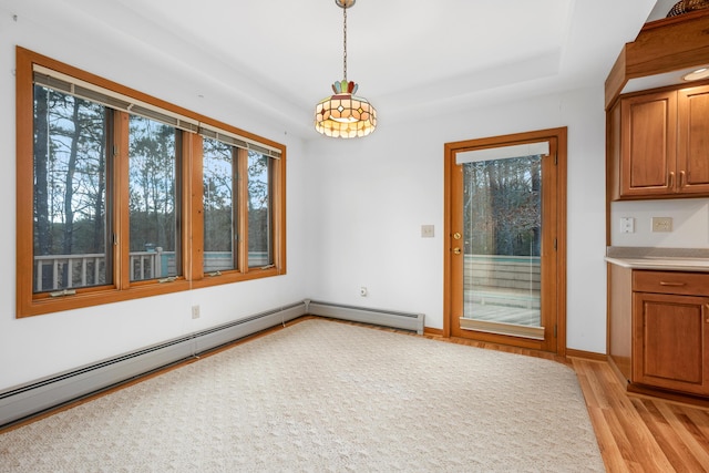 unfurnished dining area with a tray ceiling, light hardwood / wood-style flooring, and a baseboard radiator