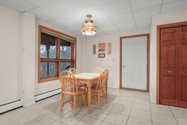 tiled dining room with baseboard heating and a drop ceiling