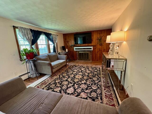 56 Wendward Way W, Yarmouth, MA 02673 - living area featuring wood walls, wood finished floors, a brick fireplace, and a baseboard radiator