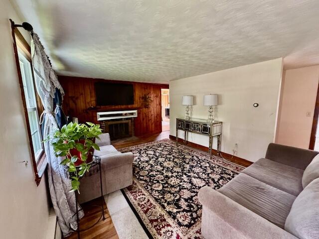 56 Wendward Way W, Yarmouth, MA 02673 - living room with wood finished floors, wood walls, a textured ceiling, and a brick fireplace