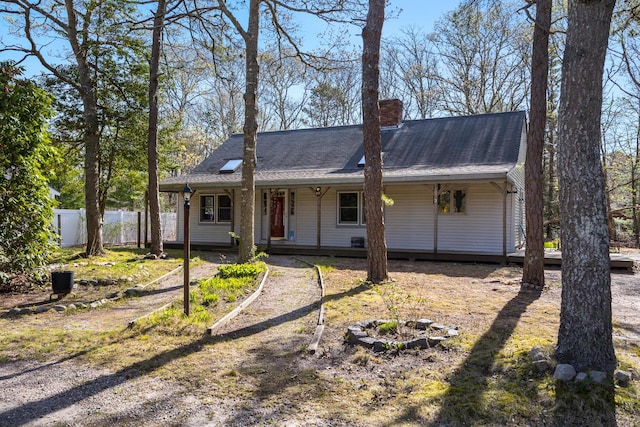 single story home featuring a chimney, a shingled roof, covered porch, and fence