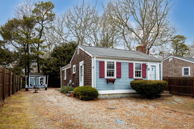 52 Nauset Rd, West Yarmouth, MA 02673 - view of side of home featuring an outdoor structure, fence, a shed, and a chimney