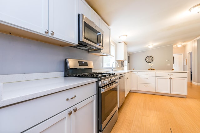 248 Mattapoisett Rd, Acushnet, MA 02743 - kitchen featuring stainless steel appliances, light wood finished floors, light countertops, a peninsula, and white cabinets