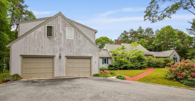 24 Indigo Ln, Osterville, MA 02655 - view of front of house with a garage, a front yard, asphalt driveway, and a chimney