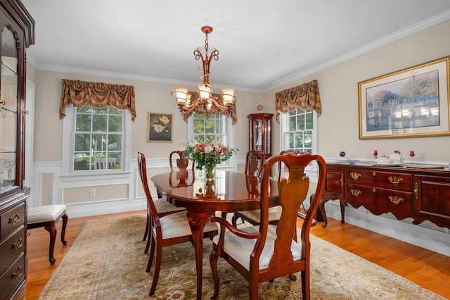 dining room with a notable chandelier, crown molding, wainscoting, and light wood finished floors