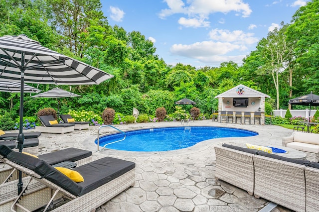 outdoor pool with a patio, fence, an outdoor structure, and outdoor dry bar