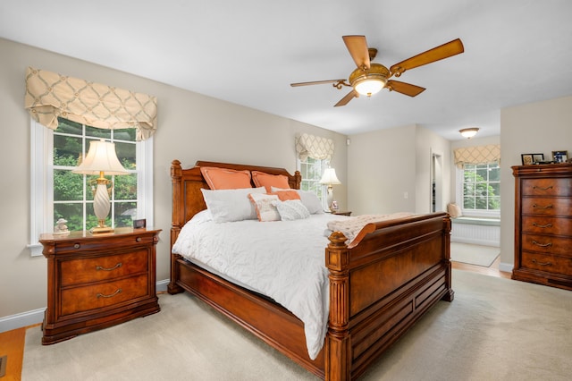 bedroom with ensuite bath, light colored carpet, a ceiling fan, and baseboards