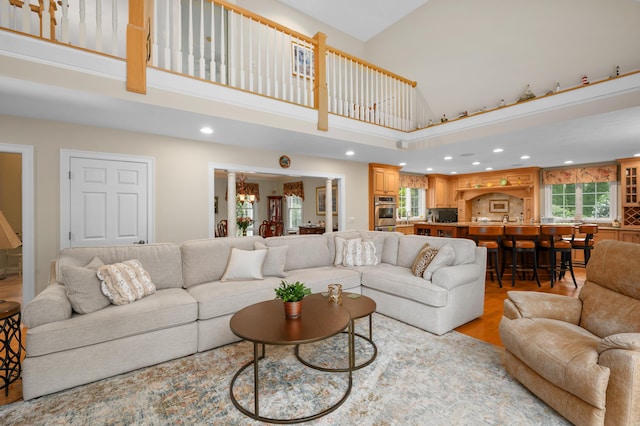 living room featuring a high ceiling, recessed lighting, light wood-type flooring, and a chandelier