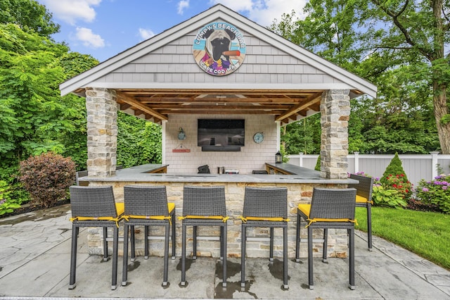 view of patio / terrace featuring a bar and fence