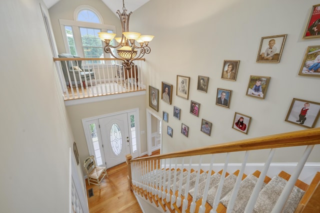 foyer entrance featuring a chandelier, high vaulted ceiling, and wood finished floors