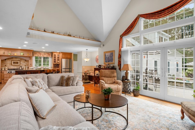 living area with light wood finished floors, recessed lighting, high vaulted ceiling, and a wealth of natural light