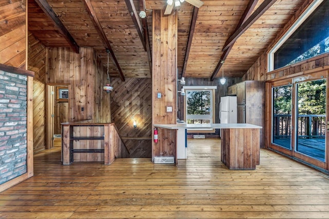 kitchen featuring lofted ceiling with beams, wooden ceiling, wooden walls, a peninsula, and light countertops