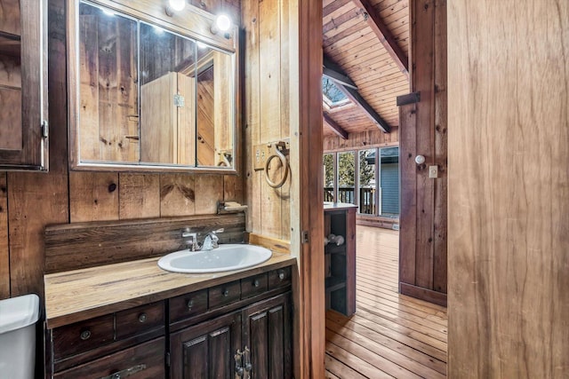 bathroom featuring toilet, wood walls, wooden ceiling, and vanity