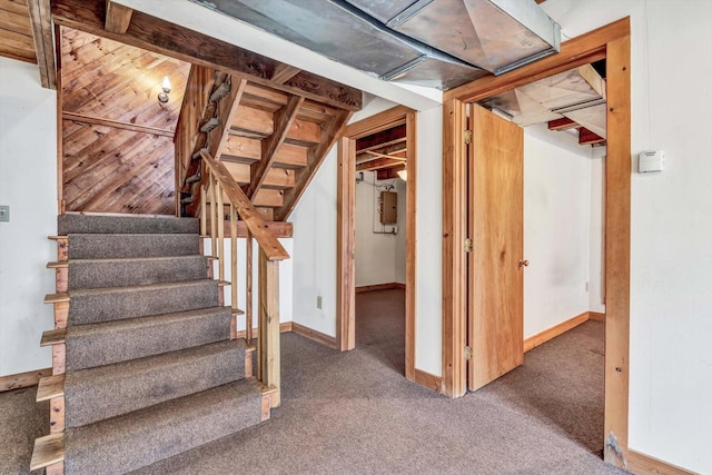 finished basement featuring baseboards, electric panel, stairway, and dark colored carpet