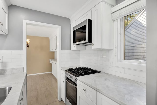 kitchen with white cabinets, stainless steel appliances, light stone countertops, and decorative backsplash