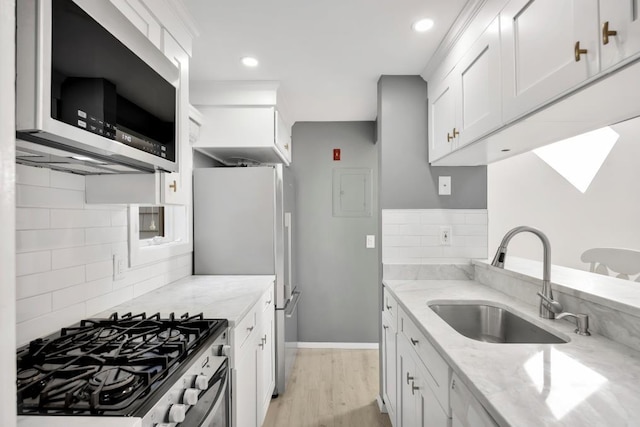 kitchen with light stone countertops, tasteful backsplash, white cabinets, sink, and stainless steel appliances