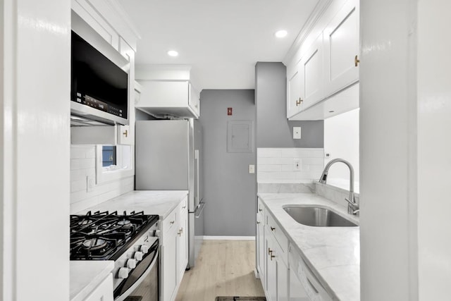 kitchen with light stone counters, sink, white cabinetry, and stainless steel appliances