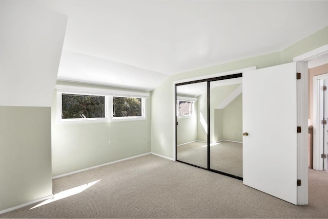 unfurnished bedroom featuring a closet, light colored carpet, and lofted ceiling