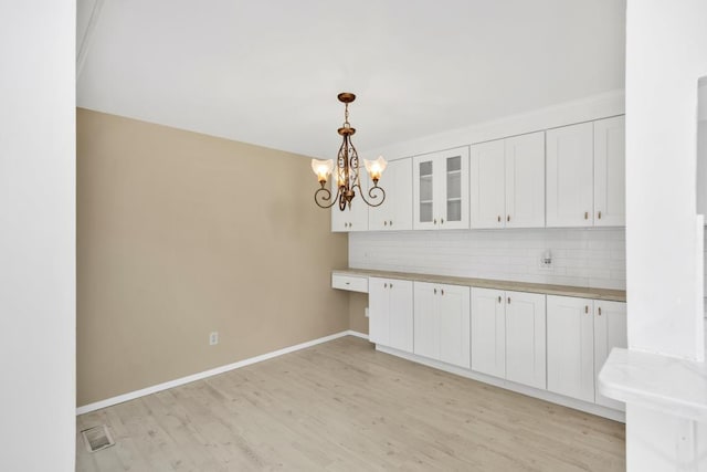 kitchen featuring white cabinetry, butcher block counters, tasteful backsplash, light hardwood / wood-style floors, and hanging light fixtures