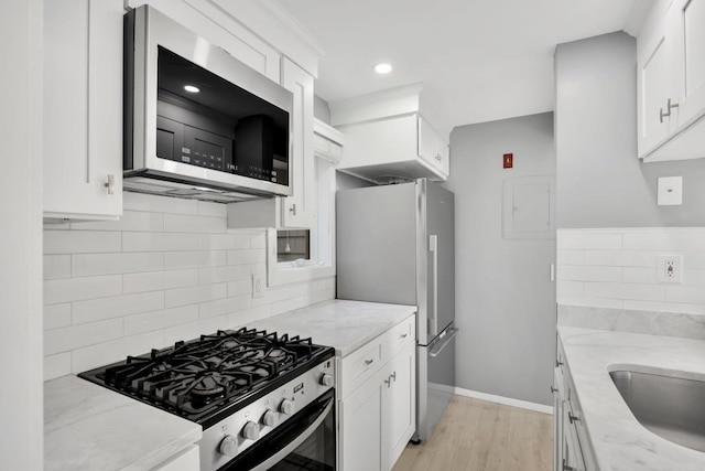 kitchen featuring stainless steel appliances, white cabinetry, and light stone countertops