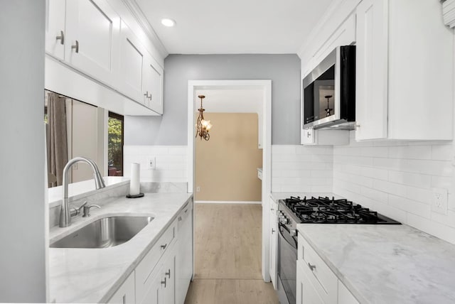 kitchen featuring sink, white cabinetry, light stone countertops, a chandelier, and stainless steel appliances