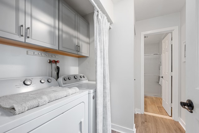 washroom featuring light wood-type flooring, cabinet space, and independent washer and dryer