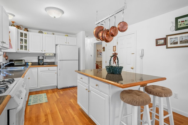 kitchen with white cabinetry, white appliances, and a breakfast bar area