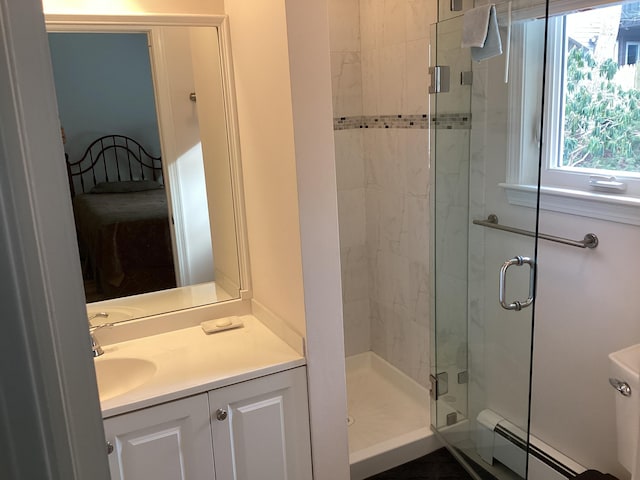 bathroom with a shower with shower door, baseboard heating, and vanity