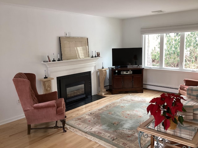 living room with crown molding, baseboard heating, and light hardwood / wood-style floors